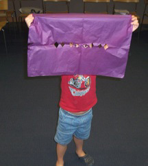 child peering out through the holes in his papel picado