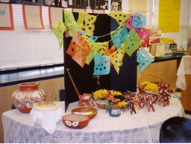 The photo shows the children's altar displaying papel picado and artifacts related to El d&iacute;a de los muertos