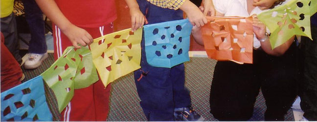 The children are holding a string of papel picado.