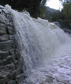 Close up photograph of floodwater flowing over the bridge