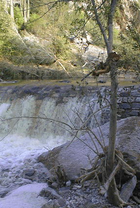 Photograph of flood water pouring over the first bridge.